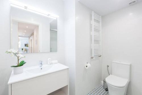 een witte badkamer met een wastafel en een spiegel bij NEW Gorgeous Central Apartment - Beachfront - 3 BD in San Sebastian