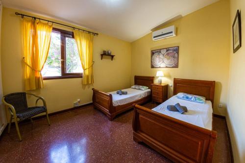 a bedroom with two beds and a chair and a window at Villa Punta Negra HEATED POOL tenerifesummervillas in Puerto de Santiago