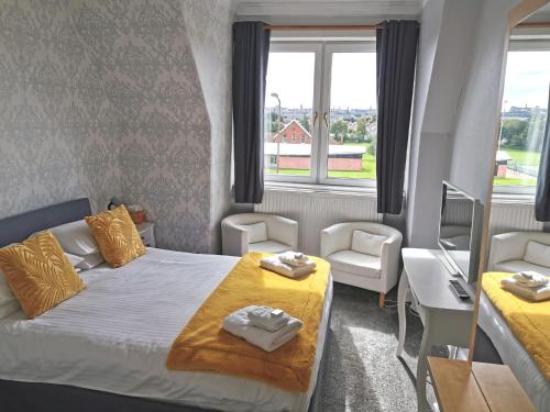 Cette petite chambre comprend un lit, un bureau et 2 fenêtres. dans l'établissement Brig O'Doon Guest House, à Édimbourg