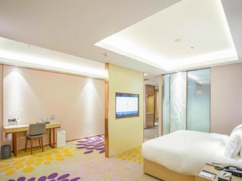 Habitación de hotel con cama, escritorio y TV. en Lavande Hotel Jinzhou Jiefang Road Kaixuan Building en Jinzhou
