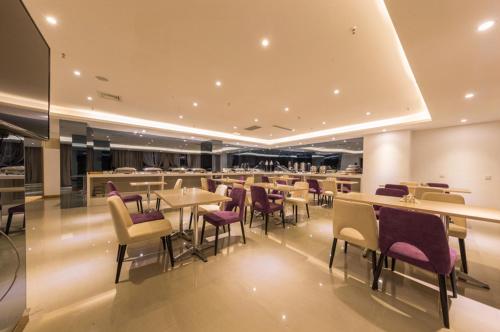 un restaurante con mesas, sillas y sillas moradas en Lavande Hotel (Linyi Yinan Junyue Shopping Center Branch), en Yinan