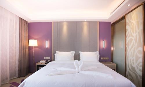 a large white bed in a room with purple walls at Lavande Hotel (Changchun Yiqi Branch) in Changchun