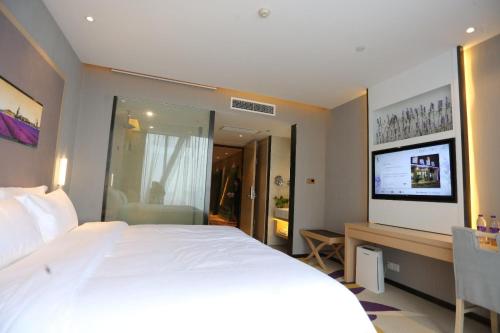 a bedroom with a bed and a desk with a television at Lavande Hotel Shijiazhuang Zhonghua North Street Zhongchu Plaza Branch in Shijiazhuang