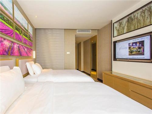 a bedroom with two beds and a flat screen tv at Lavande Hotel (Ganzhou Golden Plaza Branch) in Ganzhou