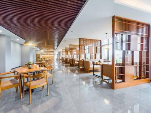 una sala da pranzo con tavoli e sedie in un edificio di Lavande Hotel Wuxi Taihu Avenue a Wuxi