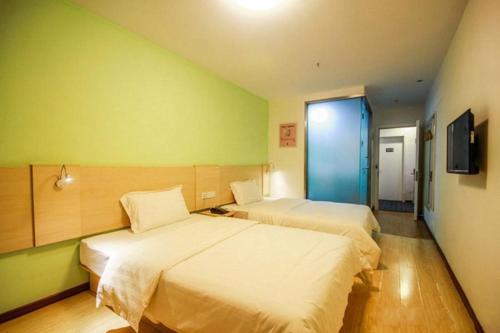 um quarto de hotel com duas camas e uma televisão em 7Days Inn Turpan Dashizi em Turfan