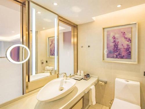 ein weißes Badezimmer mit einem Waschbecken und einem Spiegel in der Unterkunft Lavande Hotel Nanchang Shuanggang Metro Station Caida University in Nanchang