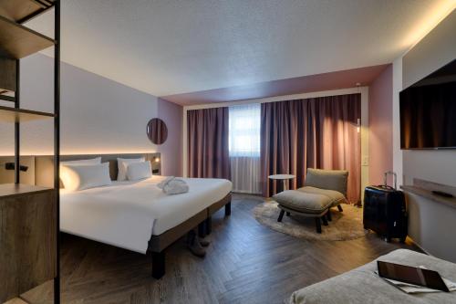 a hotel room with a large bed and a chair at Novotel Zurich City West in Zürich