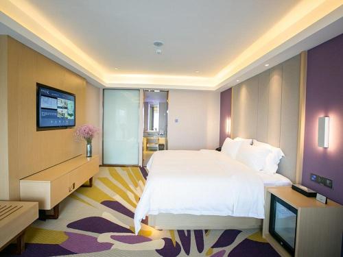 ein Schlafzimmer mit einem großen weißen Bett und einem TV in der Unterkunft Lavande Hotel (Nanchang Qianhu Avenue Nanchang Univercity Branch) in Nanchang