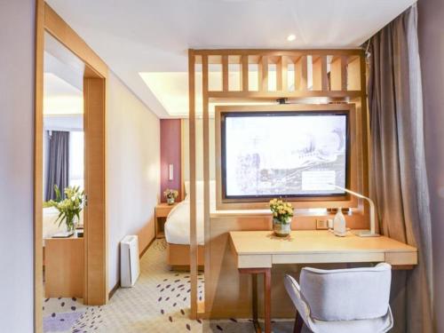 a hotel room with a desk and a bed at Lavande Hotel (Shenyang Olympic Center Wanda Branch) in Shenyang