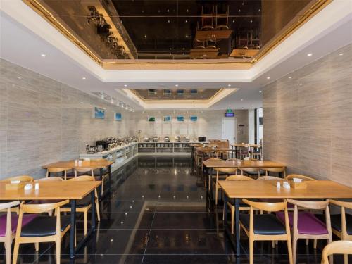 Lavande Hotel Guangzhou Sunac Cultural Tourism City Branch في هوادو: غرفة طعام مع طاولات وكراسي خشبية