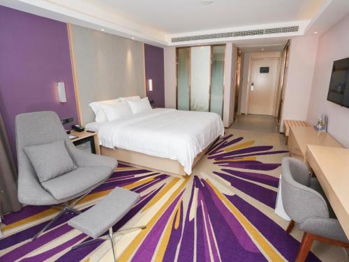 a hotel room with a bed and two chairs at Lavande Hotel Zhoushan Putuo in Zhoushan