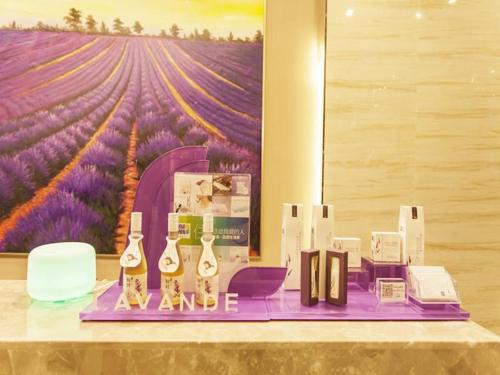 Lavande Hotel Jinzhong Yuci Walmart Branch في Jinzhong: طاولة مع زجاجات من النبيذ و لوحة لميدان الأفرنجي