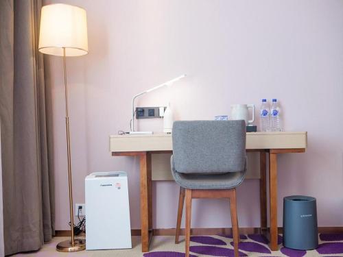 a desk with a chair and a lamp in a room at Lavande Hotel Jinzhou Jiefang Road Kaixuan Building in Jinzhou