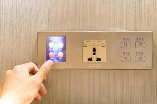 una persona está apuntando a un interruptor electrónico en Lavande Hotel Nanchang Qingshanhu Wanda Branch en Nanchang