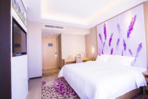 a bedroom with a large white bed and a kitchen at Lavande Hotel Xinyang Municipal Government Branch in Xinyang