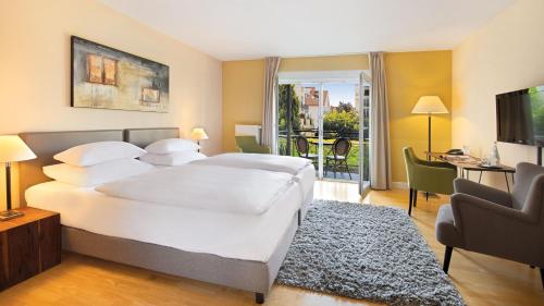 a bedroom with a large white bed and a living room at Hotel Villa Toskana in Leimen