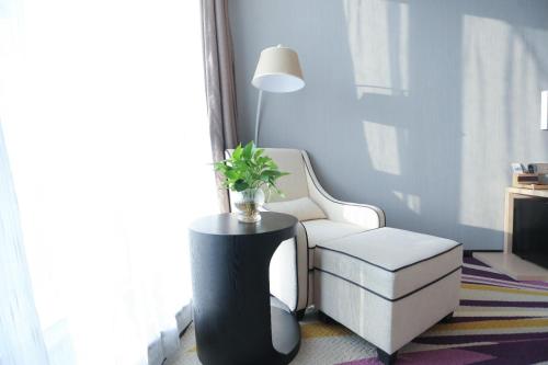 a living room with a white chair and a plant at Lavande Hotel Shijiazhuang Zhonghua North Street Zhongchu Plaza Branch in Shijiazhuang