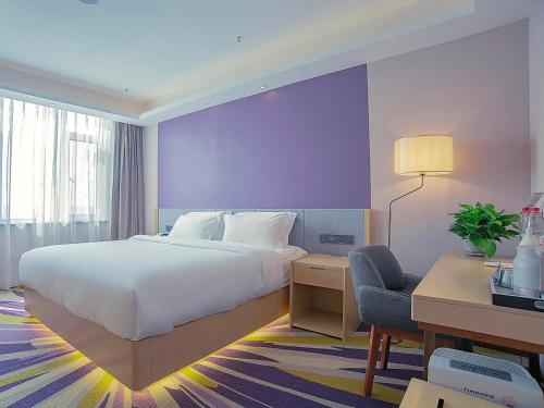a bedroom with a bed and a desk and a chair at Lavande Hotel Handan Congtai Park New Century Plaza in Handan