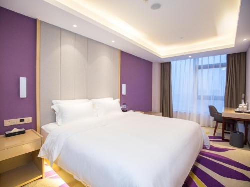 a bedroom with a large white bed and a desk at Lavande Hotel (Nanchang West Railway Station Square Branch) in Nanchang