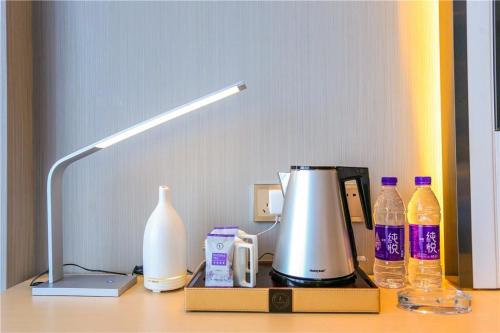 a desk with a lamp and a coffee maker and bottles at Lavande Hotel Shijiazhuang Zhonghua North Street Zhongchu Plaza Branch in Shijiazhuang