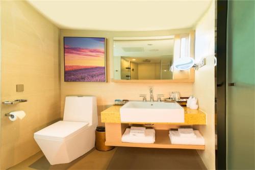 a bathroom with a sink and a toilet and a mirror at Lavande Hotel Rizhao Rong'an Square Wanda Movie Theater Branch in Rizhao
