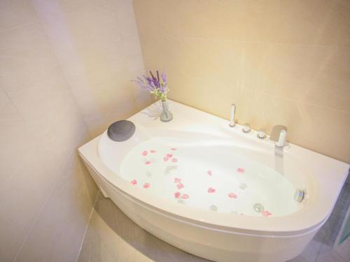 a bathroom with a bath tub with a vase of flowers at Lavande Hotel (Zibo Beijing Road Huaqiao Building Branch) in Zibo