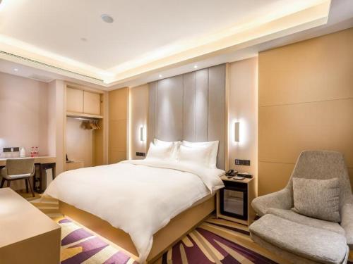 - une chambre avec un grand lit blanc et une chaise dans l'établissement Lavande Hotel Langfang City Government, à Langfang