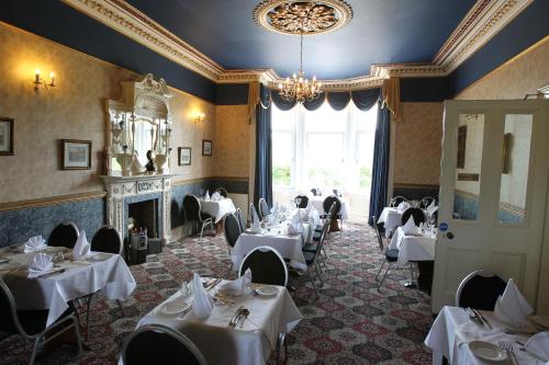 uma sala de jantar com mesas brancas e um lustre em Cressfield Country House Hotel em Ecclefechan