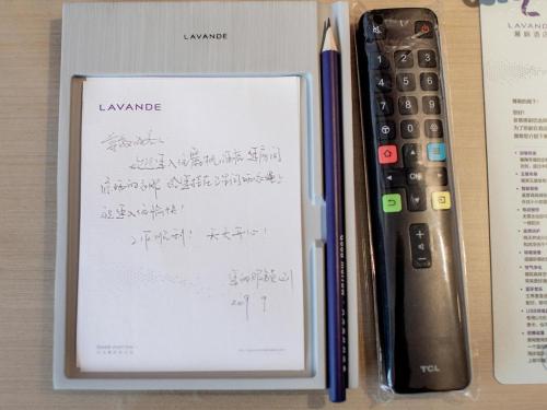 a book with writing on it next to a remote control at Lavande Hotel Changsha Xingsha Center in Xingsha