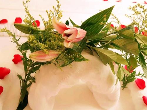 a white vase with flowers and leaves on a table at Lavande Hotel Jinan Second Ring East Road Quanfu Overpass Branch in Jinan