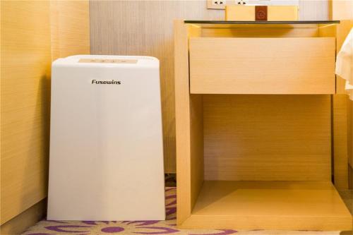 a white refrigerator sitting in a closet next to a desk at Lavande Hotel Rizhao Rong'an Square Wanda Movie Theater Branch in Rizhao