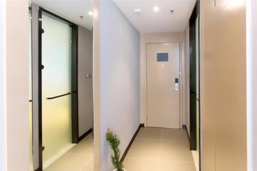 a hallway with a door and a hallway with a plant at Lavande Hotel Rizhao Rong'an Square Wanda Movie Theater Branch in Rizhao