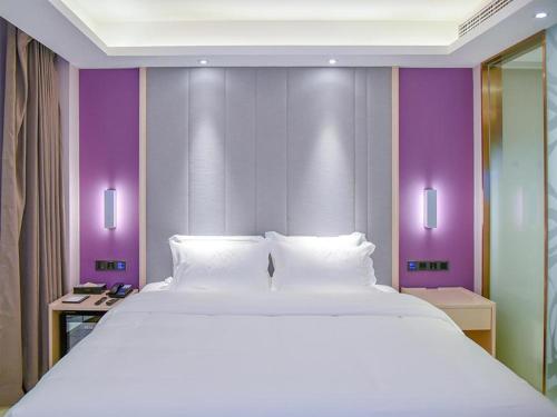 a large white bed in a room with purple walls at Lavande Hotel Enshi Cultural Center in Enshi