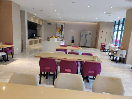 a dining room with tables and chairs in a cafeteria at Lavande Hotel (Nanchang West Railway Station Square Branch) in Nanchang