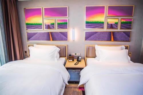 two beds in a room with a painting on the wall at Lavande Hotel Xiaogan Beijing Road Branch in Xiaogan