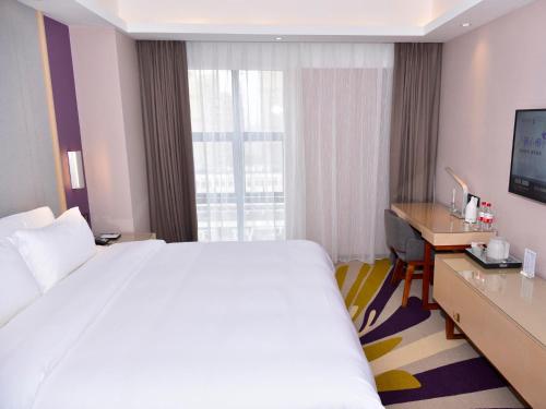 a hotel room with a large bed and a desk at Lavande Hotel Fuzhou Wanda Plaza High-speed Railway Station in Fuzhou