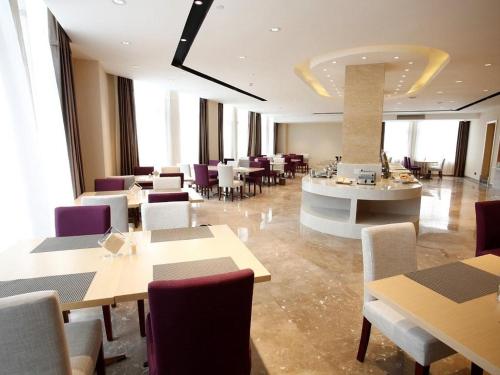 a restaurant with tables and chairs in a room at Lavande Hotel Jiujiang Jiujiang College in Jiujiang