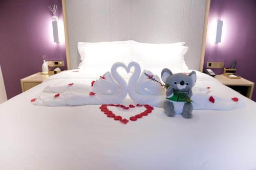 a bed with two valentines hearts and a teddy bear at Lavande Hotel (Harbin Ice and Snow World University of Commerce Branch) in Harbin