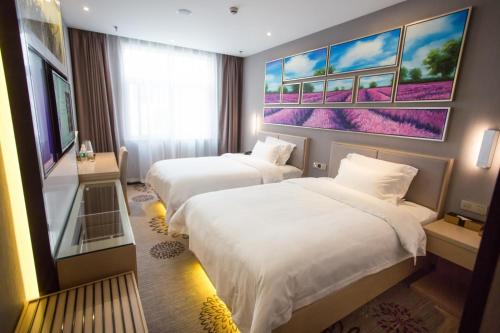 a hotel room with two beds and a painting on the wall at Lavande Hotel Xuzhou East High-speed Rail Station Jinshanqiao Development Zone Branch in Xuzhou