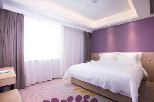 a bedroom with a large bed and a purple wall at Lavande Hotel (Changchun Yiqi Branch) in Changchun