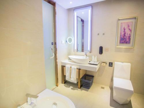 a white bathroom with a sink and a toilet at Lavande Hotel (Zibo Beijing Road Huaqiao Building Branch) in Zibo