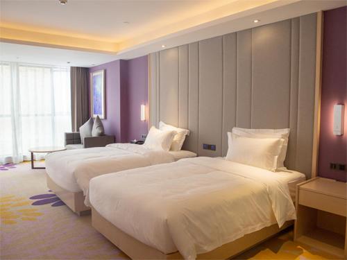 2 Betten in einem Hotelzimmer mit lila Wänden in der Unterkunft Lavande Hotel Enshi Cultural Center in Enshi