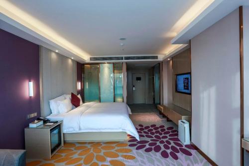 1 dormitorio con 1 cama y TV en Lavande Hotel (Linyi Yinan Junyue Shopping Center Branch), en Yinan