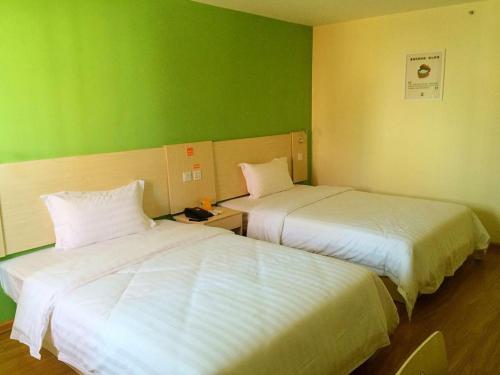 two beds in a room with green walls at 7Days Inn Qiongzhong Zero Kilometer in Qiongzhong