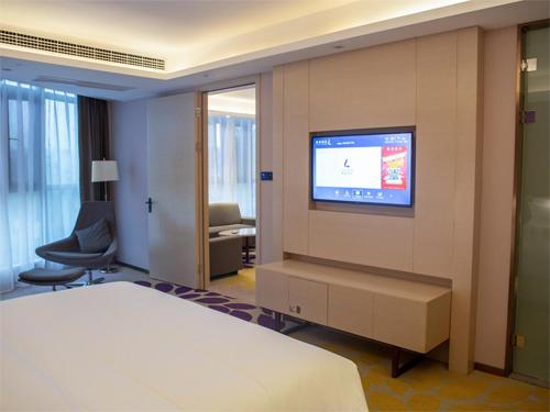 a hotel room with a bed and a tv on a wall at Lavande Hotel Enshi Cultural Center in Enshi