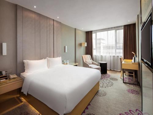 a hotel room with a large white bed and a desk at Lavande Hotel Hengyang Changsheng West Road Nanhua University in Hengyang