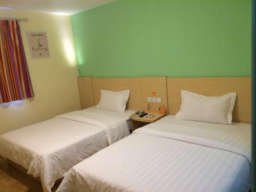 two beds in a room with green walls at 7Days Inn Bijie Zhijin Chengguan in Zhijin