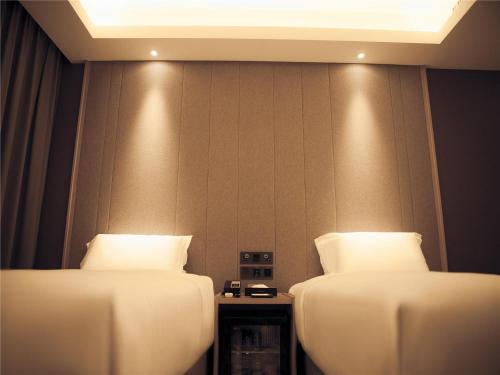 two beds in a hotel room with lights on the wall at Lavande Hotel Qiqihar Supervisory Office in Qiqihar