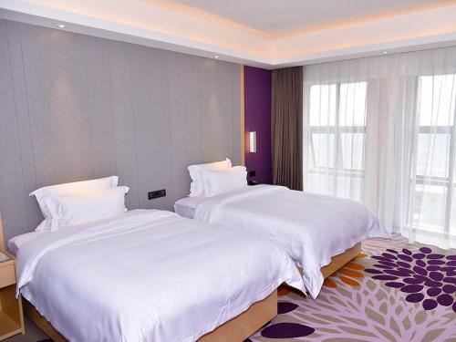 two beds in a hotel room with white sheets at Lavande Hotel Fuzhou Wanda Plaza High-speed Railway Station in Fuzhou